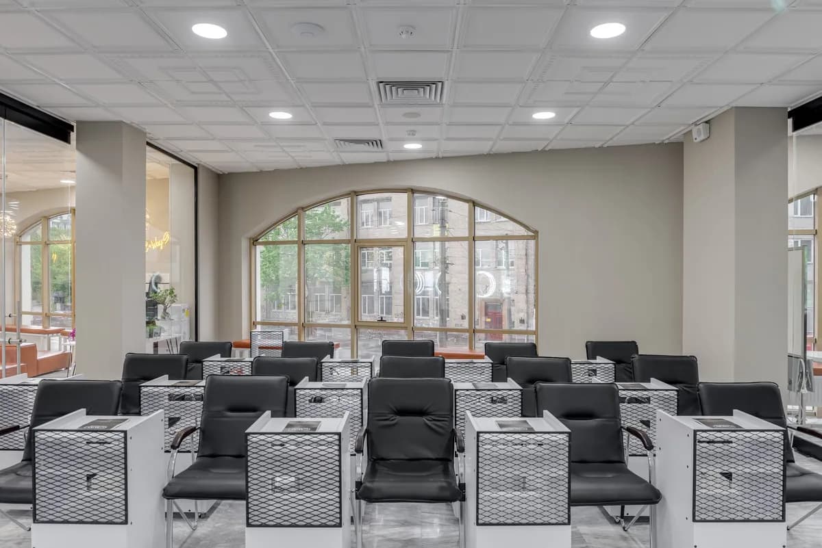Spacious salon with black leather chairs and large glass windows for natural light.