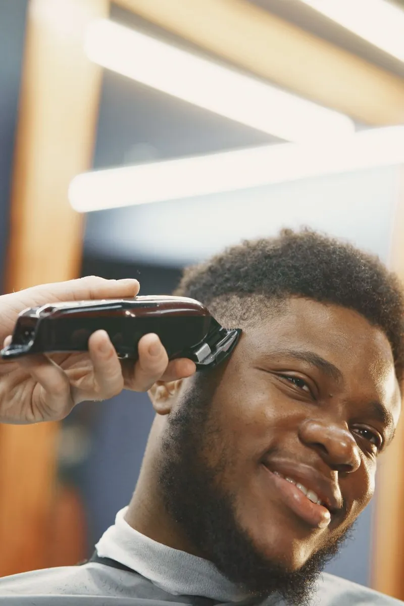 Smiling man gets a haircut at a stylish barber shop, showcasing grooming and self-care.