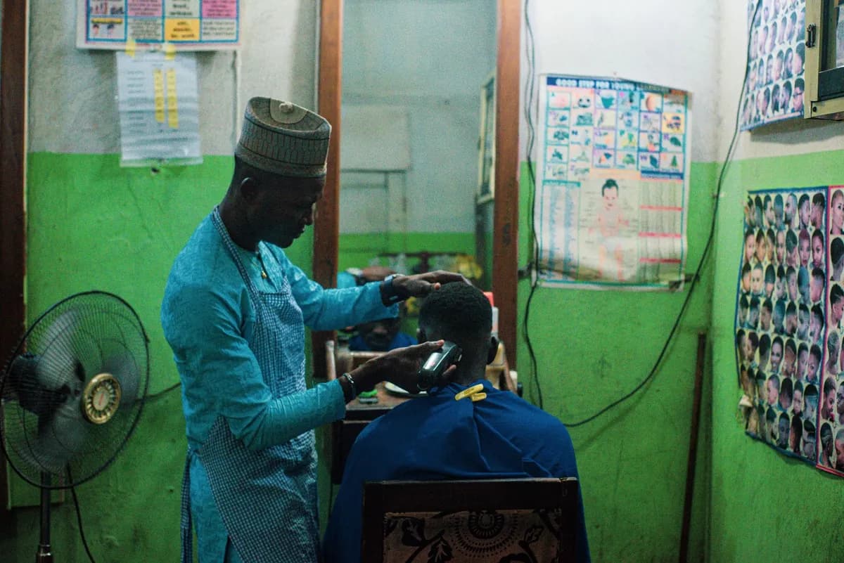 Barber using clippers to cut hair in a vintage barbershop setting.