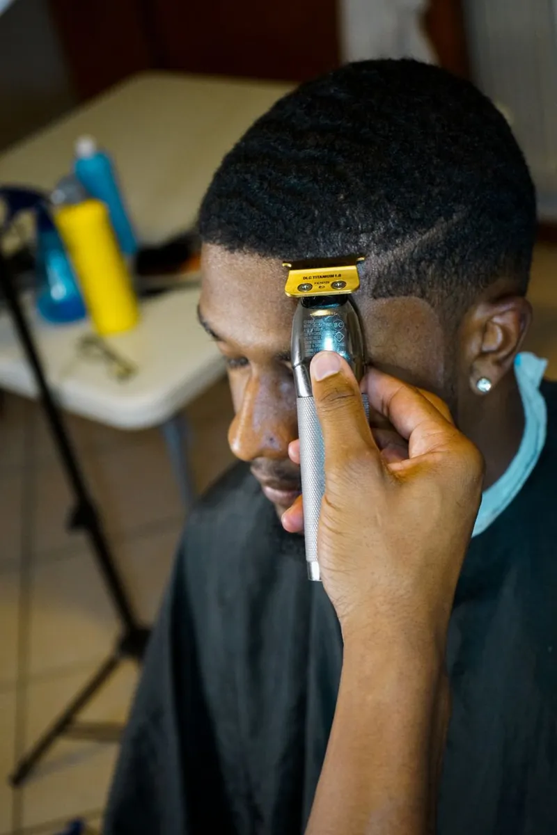 A barber trims a man's hair with precision using clippers in a salon.
