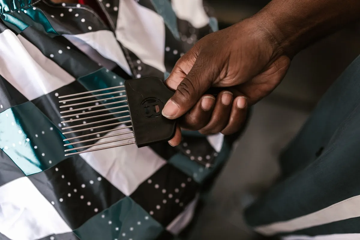 A close-up view of an African American man holding a barber tool, showcasing details of a barbershop setting.