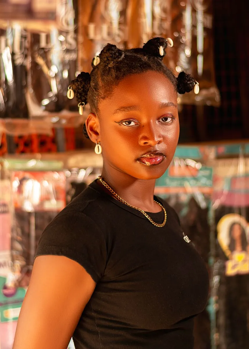 A striking portrait of a young woman with traditional hairstyle in a Nigerian hair salon.